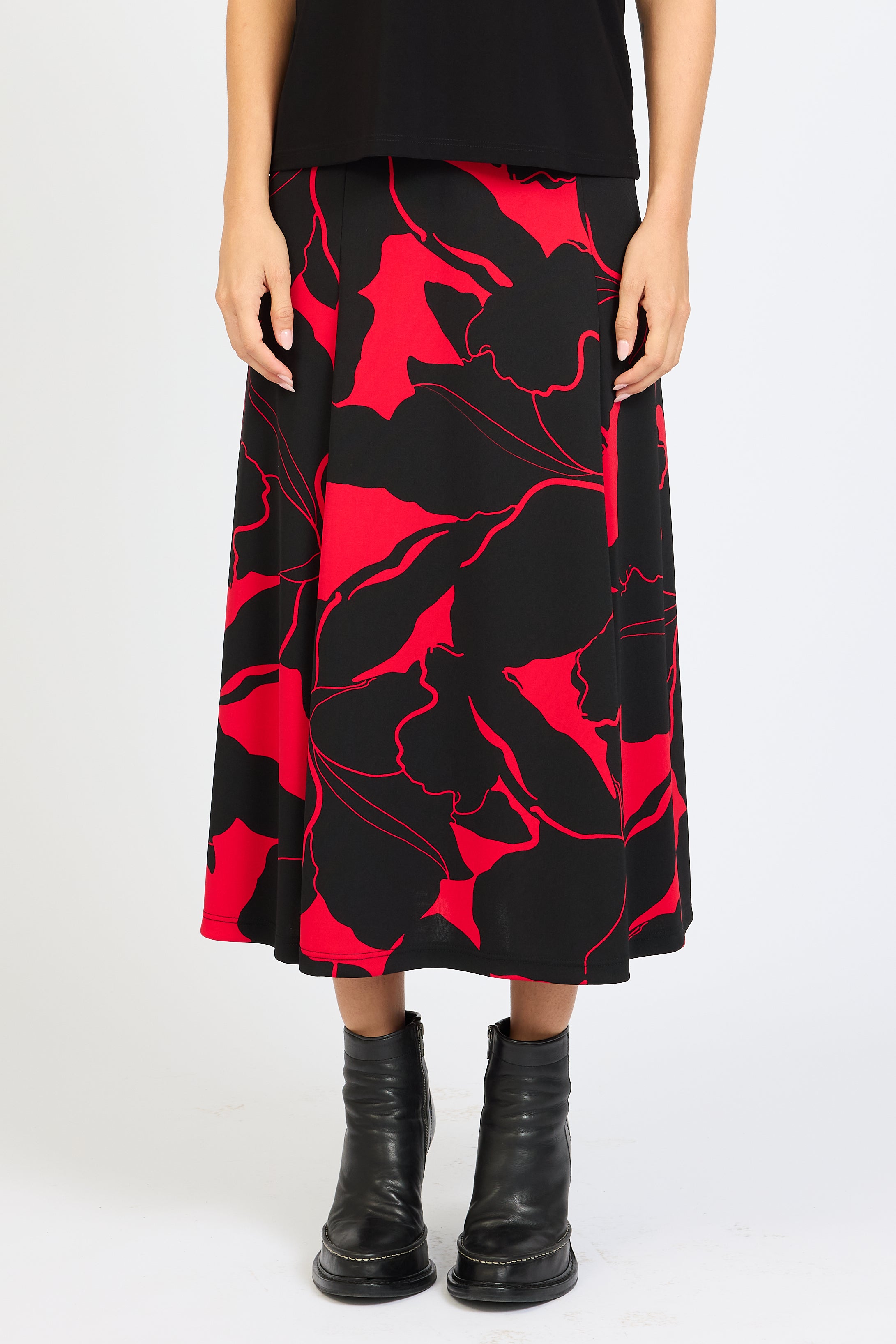 Person wearing a black and red floral patterned skirt with black boots on a white background