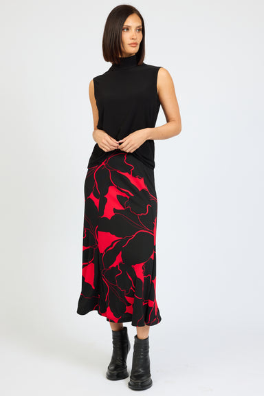 Woman wearing a black sleeveless top and red patterned skirt on a white background