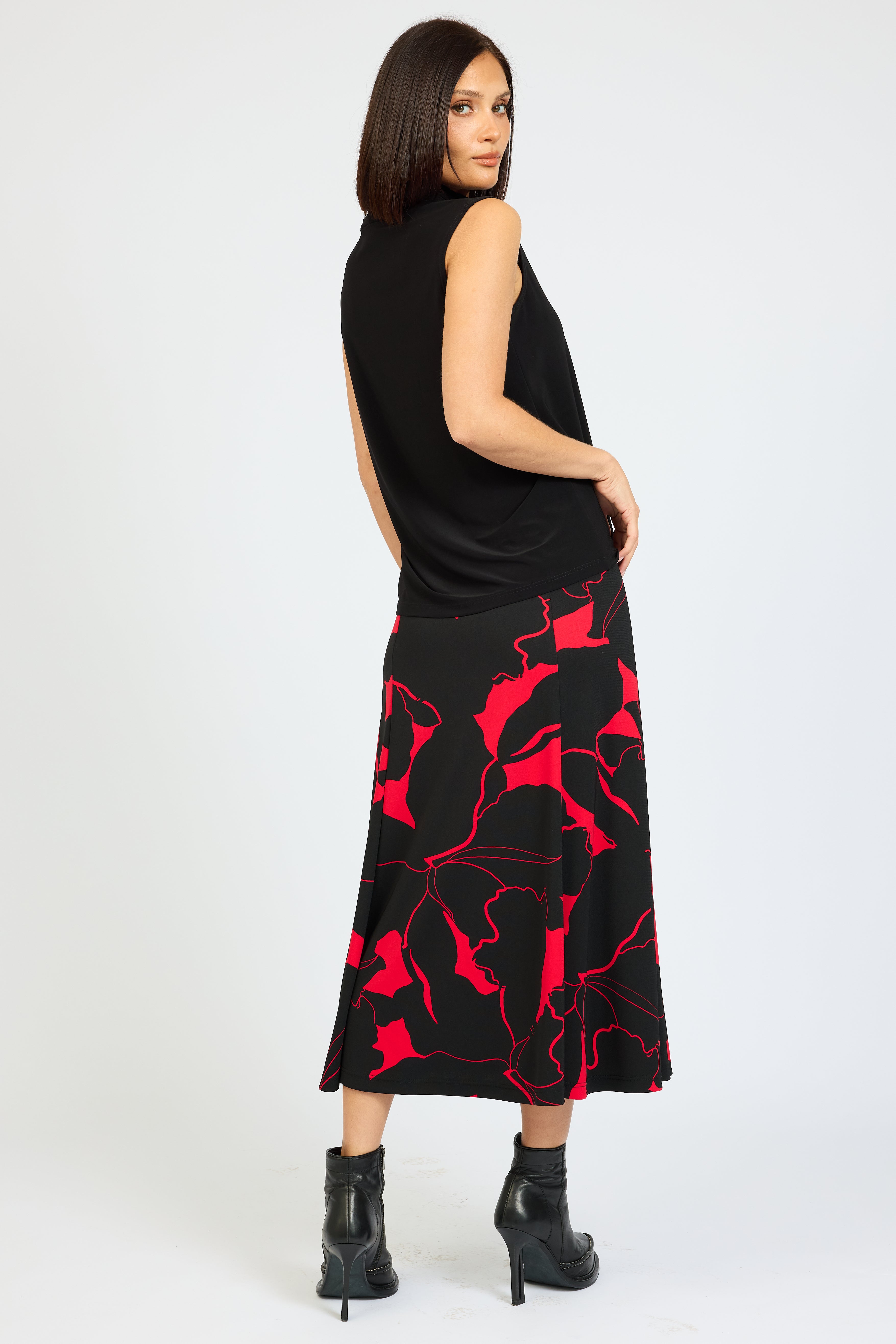 Woman wearing a black sleeveless top and red patterned skirt on a white background